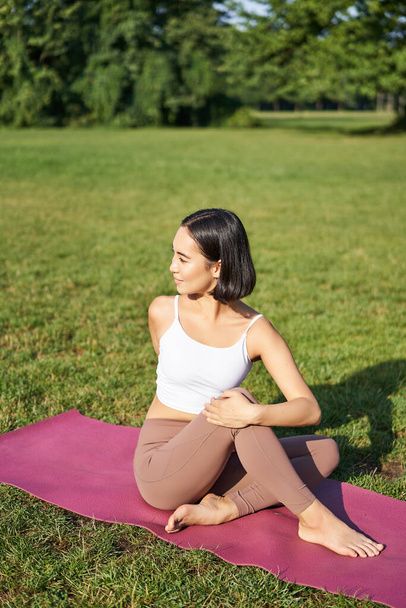Mulher meditando no parque no tapete de borracha, sentado no gramado verde e praticar ioga, conceito de esporte e bem-estar. - Foto, Imagem