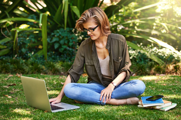 Connecté où qu'elle aille. une jeune femme attrayante utilisant son ordinateur portable tandis que dehors sur l'herbe - Photo, image