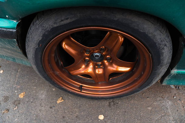 naladěné zelené auto na kovové spálené oranžové ráfky špinavé na podzim - Fotografie, Obrázek