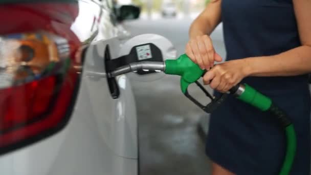 La mujer inserta una pistola de combustible en un tanque de gasolina para repostar un coche. Concepto de aumento de los precios de la gasolina, crisis del combustible - Metraje, vídeo