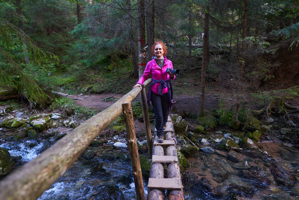 Vrouwelijke wandelaar met camera op avontuur in de bergen, door de dennenbossen - Foto, afbeelding