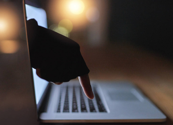 A számítástechnikai bűnözés egyre nagyobb veszélyt jelent mindenki számára. egy hackerek testetlen kéz nyúlt át egy laptop képernyőn - Fotó, kép