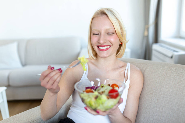 Mladá fit žena jíst zdravý salát po cvičení. Fitness a zdravý životní styl koncepce. zdravá mladá žena jíst zelený salát - Fotografie, Obrázek