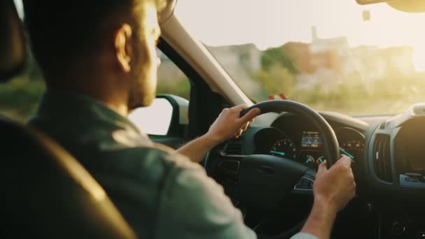 Ο άνθρωπος οδηγεί ένα αυτοκίνητο κατά μήκος του δρόμου, ο ήλιος που δύει λάμπει στο παρμπρίζ. Θέα πίσω από τον ώμο του οδηγού - Πλάνα, βίντεο