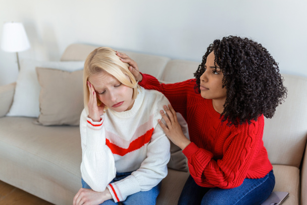 Friend trying to calm down her friend. Woman crying. Young lady sharing her problem with friend. female in depression. Woman omforting hes sad friend sitting on a couch in the living room at home - Fotografie, Obrázek