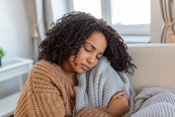 Хвора молода африканка відчуває холод, вкритий ковдрою, сидить на ліжку, хвора чорна дівчина, що замерзає, прогрівається вдома, загорнута пледом, без центральної проблеми з підігрівом, концепція температурного грипу
 - Фото, зображення