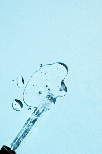 Egy üveg pipetta cseppeket öntött hidratáló krém a kék háttér. Lapos fektetés, függőleges kép. - Fotó, kép