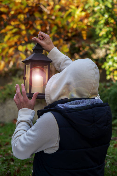 Un homme en sweat à capuche tient une lanterne lumineuse devant lui. Concept : coupure de courant, recherche de routes, sélection de sentiers. - Photo, image