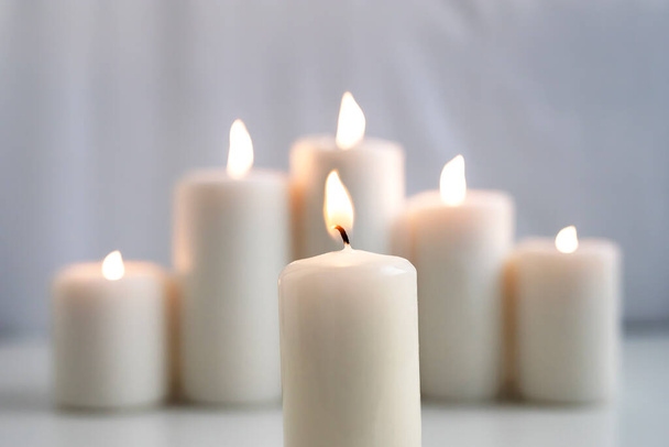 Large burning wax candles on a white background. - Foto, Imagen