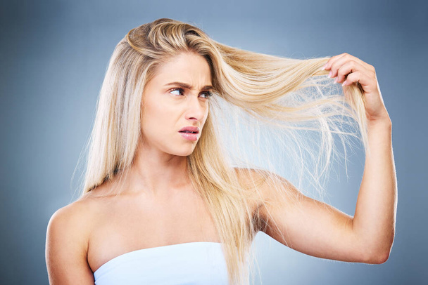 Upset, angry and annoyed woman with hair problem or style issue on a grey studio background. Damage, bad and expression of female unhappy with blonde hair loss for advertisement on a backdrop. - Fotoğraf, Görsel