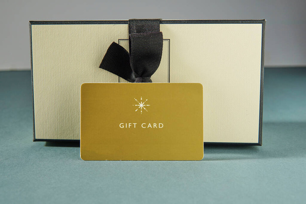 Κίτρινη δωροκάρτα και κουτί δώρου σε πράσινο φόντο. δωροκάρτα ή δώρο - Φωτογραφία, εικόνα