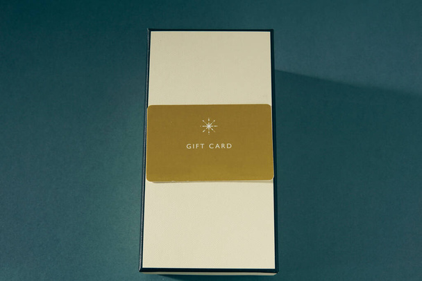 Tarjeta de regalo amarilla y una caja de regalo sobre fondo verde. tarjeta de regalo o regalo - Foto, imagen