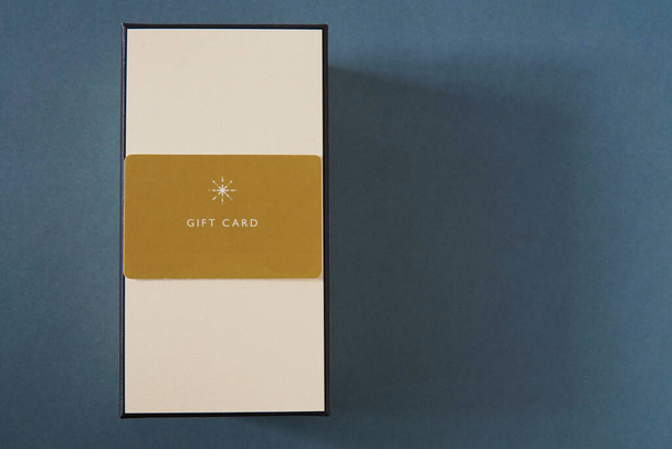 Gelbe Geschenkkarte und ein Geschenkkarton vor grünem Hintergrund. Gutschein oder Geschenk - Foto, Bild