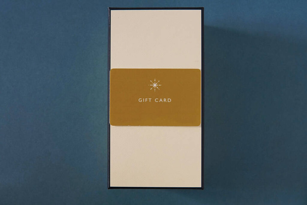 Sarı hediye kartı ve yeşil arka plana karşı bir hediye kutusu. hediye kartı ya da hediye kartı - Fotoğraf, Görsel