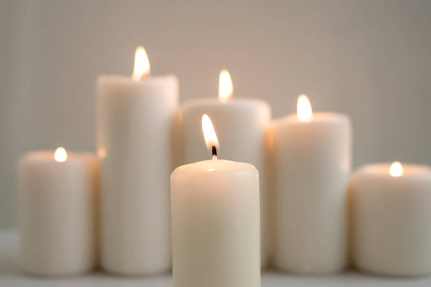 Lighted candle against the background of burning candles and glare. - Photo, image