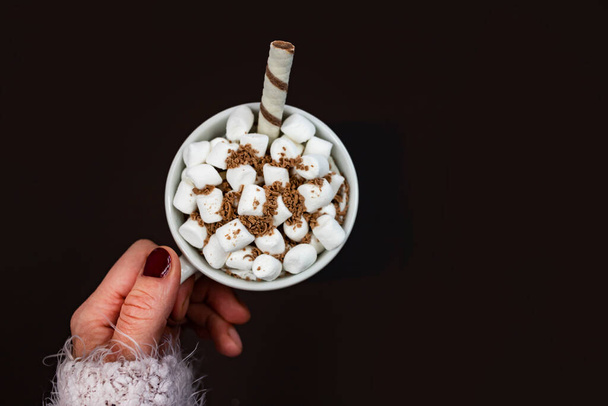 Hot chocolate with marshmallows in female hands on a dark background. Top view, place for text. Christmas celebration and New Year coming concept. - Foto, Imagem