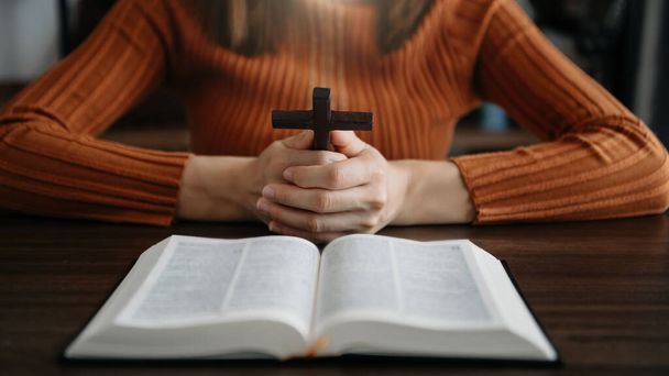 partial view of religious woman Hands at table with cross and bible book  - Photo, Image