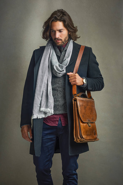 People will stare, so make it worth their while. a stylishly dressed man posing with a leather satchel in the studio - Фото, изображение