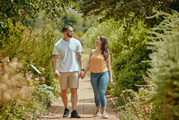 Couple, hand holding and nature park walking of people on a outdoor path with a smile. Happy girlfriend and boyfriend together showing love, care and commitment on a walk or hike feeling happiness. - Fotoğraf, Görsel