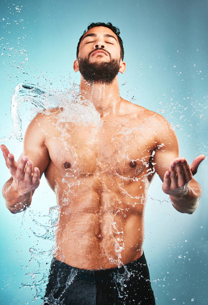Tělo, sprcha a voda s svalovcem ve studiu na modrém pozadí pro hygienu, hydrataci nebo wellness. Koupelna, silná a čistá s mladým samcem, který si myje kůži pro svěží péči. - Fotografie, Obrázek