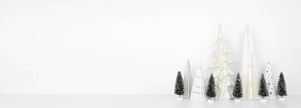 Χριστουγεννιάτικη διακόσμηση δέντρο σε ένα λευκό ράφι πάνω σε ένα λευκό φόντο banner τοίχο με αντίγραφο χώρο - Φωτογραφία, εικόνα
