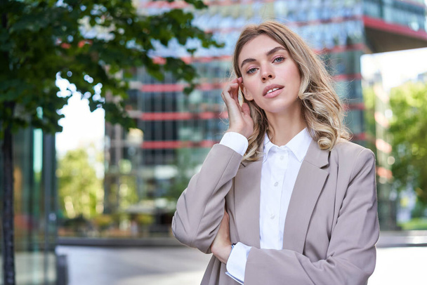 Portrait of confident corporate woman, young female ceo manager look at camera, posing in beige suit near office buildings, standing on street. - Foto, immagini