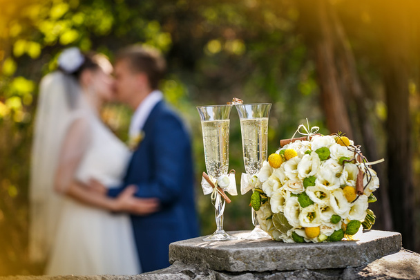 Jegygyűrű, rózsák és a pohár pezsgő és egy csókot, a vőlegény és a menyasszony a háttér - Fotó, kép