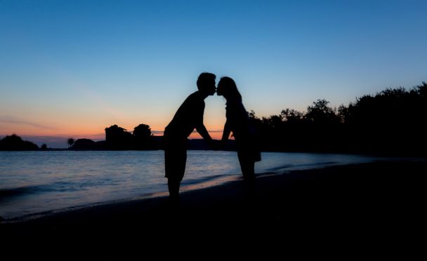 Σιλουέτα τους λάτρεις φιλιά στην παραλία στο λυκόφως - Φωτογραφία, εικόνα