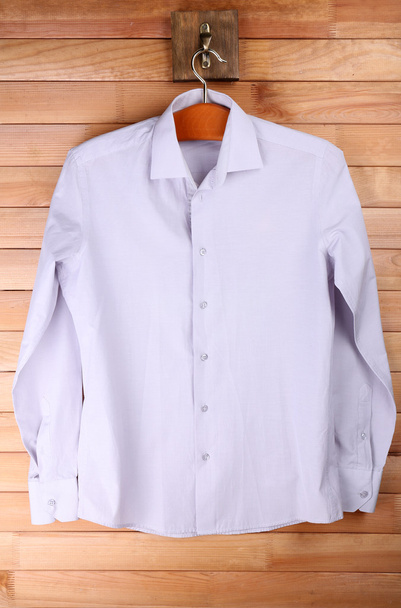 Male shirt on hanger on wooden wall background - Zdjęcie, obraz