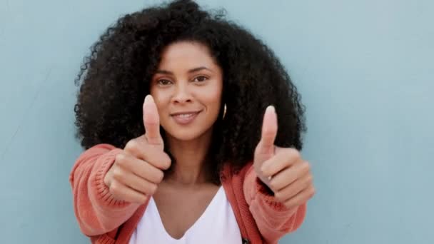 Duimen omhoog, glimlach en vrolijke zwarte vrouw die op een blauwe studio achtergrond model staat. Handen, zoals gebaar of goedkeuring, tevredenheid of oke, aanmoediging of welkom, duim signaal of ja dank u teken. - Video