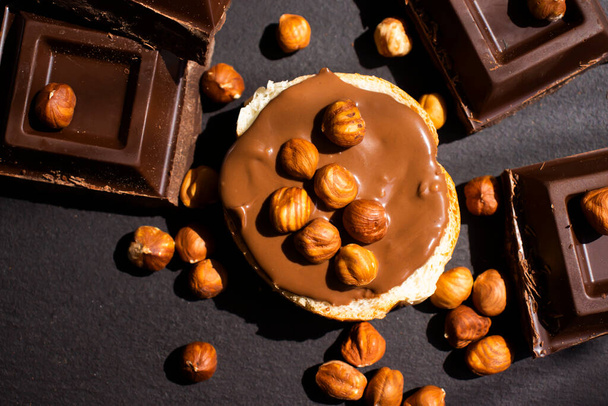 Chocolate spread, piece of bread, hazelnuts - Photo, Image