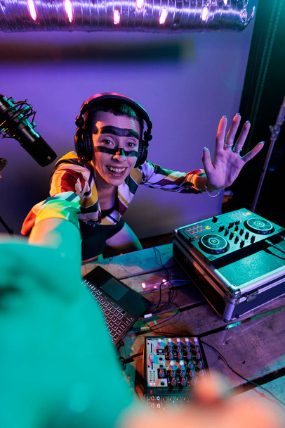 Γυναικείος παραγωγός dj που αναμιγνύει ήχους σε πικάπ, χρησιμοποιώντας κουμπιά και μπάσο για να αναμίξει techno μουσική. Μουσικός καλλιτέχνης που εκτελεί με μίξερ στο νυχτερινό κέντρο διασκέδασης, χρησιμοποιώντας ηλεκτρικό πίνακα ελέγχου, disc jockey. - Φωτογραφία, εικόνα