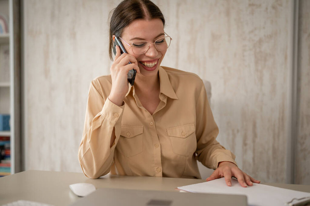 One woman female caucasian entrepreneur businesswoman or secretary sitting at her office at desk work happy smile making a phone call talk wear shirt copy space - Fotó, kép