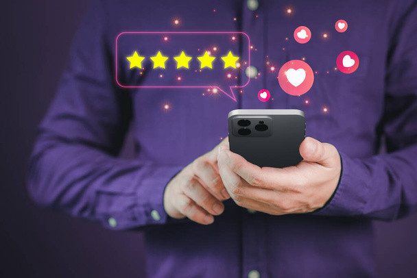 Man hand using a mobile phone with popup five star icon for feedback review satisfaction service and testimonial. Customer service experience and business satisfaction survey. - Photo, Image
