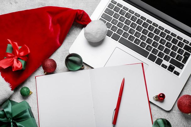 Notizbuch, Laptop, Weihnachtsmütze und Weihnachtsdekoration auf hellem Hintergrund, Nahaufnahme - Foto, Bild