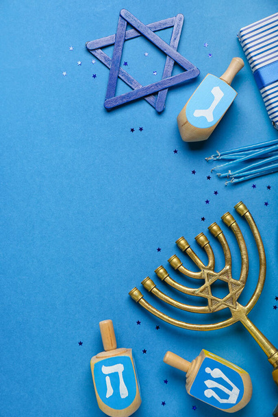 Dreidels with menorah, candles and David star for Hanukkah celebration on blue background - Photo, Image