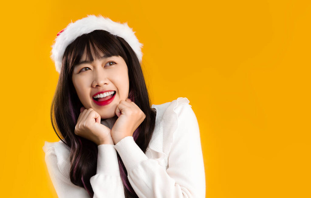 Asian woman in white blouse wear santa hat posing on yellow background. - Photo, image