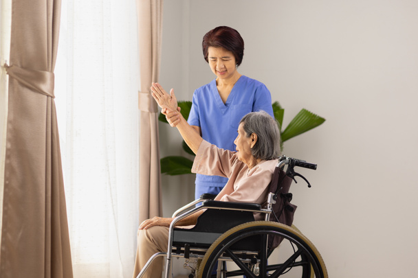 idosa mulher asiática fazendo alongamento exercício na cadeira de rodas na sala de estar em casa com fisioterapeuta. - Foto, Imagem
