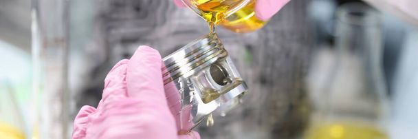 Close-up of person hand in gloves holding piston and pours lubricating oil on it. Mechanic fix car details. Lab, pit stop and service station concept - Foto, Imagem
