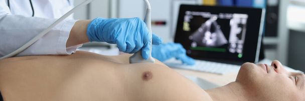 Close-up van de arts doet echografie van ribbenkast, cardioloog onderzoekt een patiënt hart. Persoon bij geplande controle in het ziekenhuis. Echografie en gezondheidszorg - Foto, afbeelding