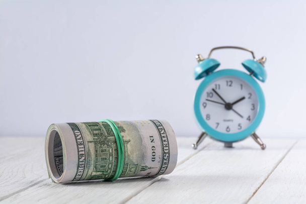 Roll of dollar bills and clock. Time is money concept - Photo, Image