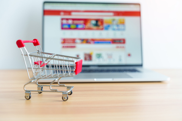 Shopping cart and laptop computer with marketplace website. business, technology, ecommerce, digital banking and online payment concept - Photo, Image