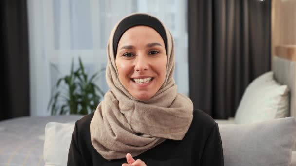 Schöne asiatische Muslimin im Hidschab macht einen Videoanruf und spricht mit der Webcam ihres Laptops. Islamische Geschäftsfrau diskutiert in einem Videotelefon, arbeitet online mit Team im Home Office - Filmmaterial, Video