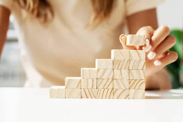 Женщина руки положить и сложить пустые деревянные кубики на стол. - Фото, изображение