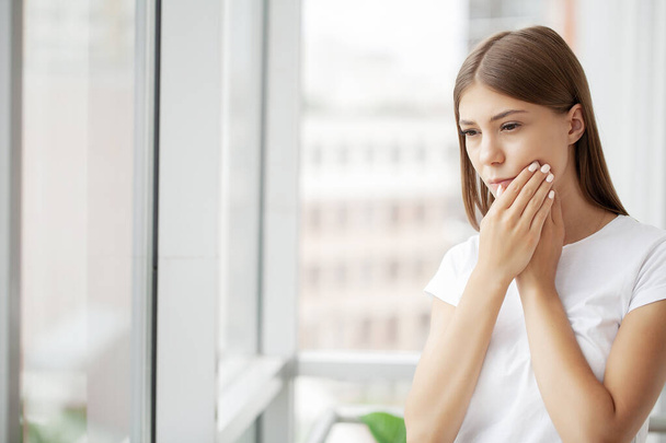 Young female business woman feels a toothache in her office. - Photo, Image