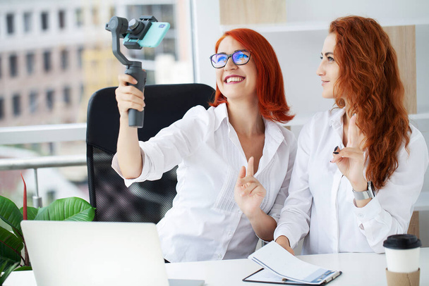 Ofiste iki kızıl saçlı iş kadını bir video blogu kaydediyor.. - Fotoğraf, Görsel