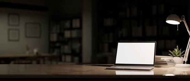 Mesa moderna do espaço de trabalho com o mockup branco da tela do portátil, luz da lâmpada de mesa e espaço da cópia sobre a sala de estar escura borrada na noite no fundo. renderização 3d, ilustração 3d - Foto, Imagem