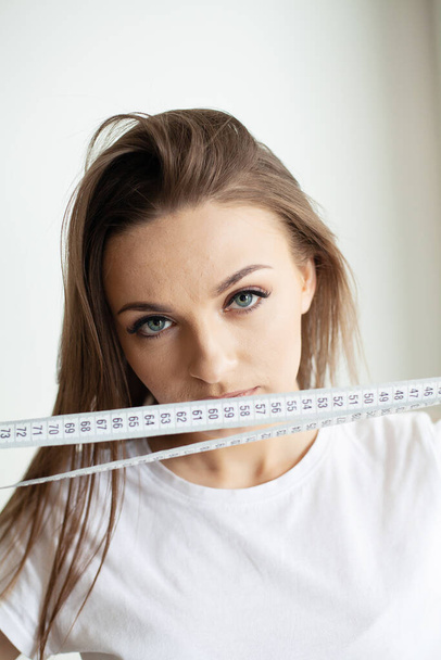 Крупним планом молода жінка тримає вимірювальну стрічку
. - Фото, зображення