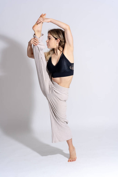 Young dancer in studio photo session with a white background, ballet, in an exercise lifting the leg - Fotografie, Obrázek