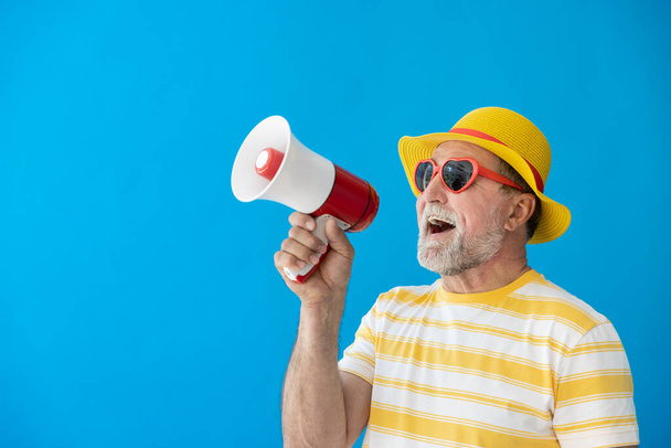 Happy senior man ready to travel. Person shouting through loudspeaker. Summer vacation and holiday concept - Photo, image